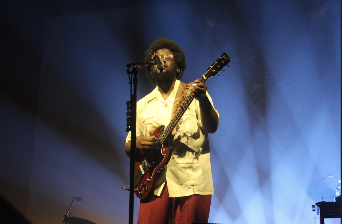 Micheal Kiwanuka playing the guitar and singing on stage