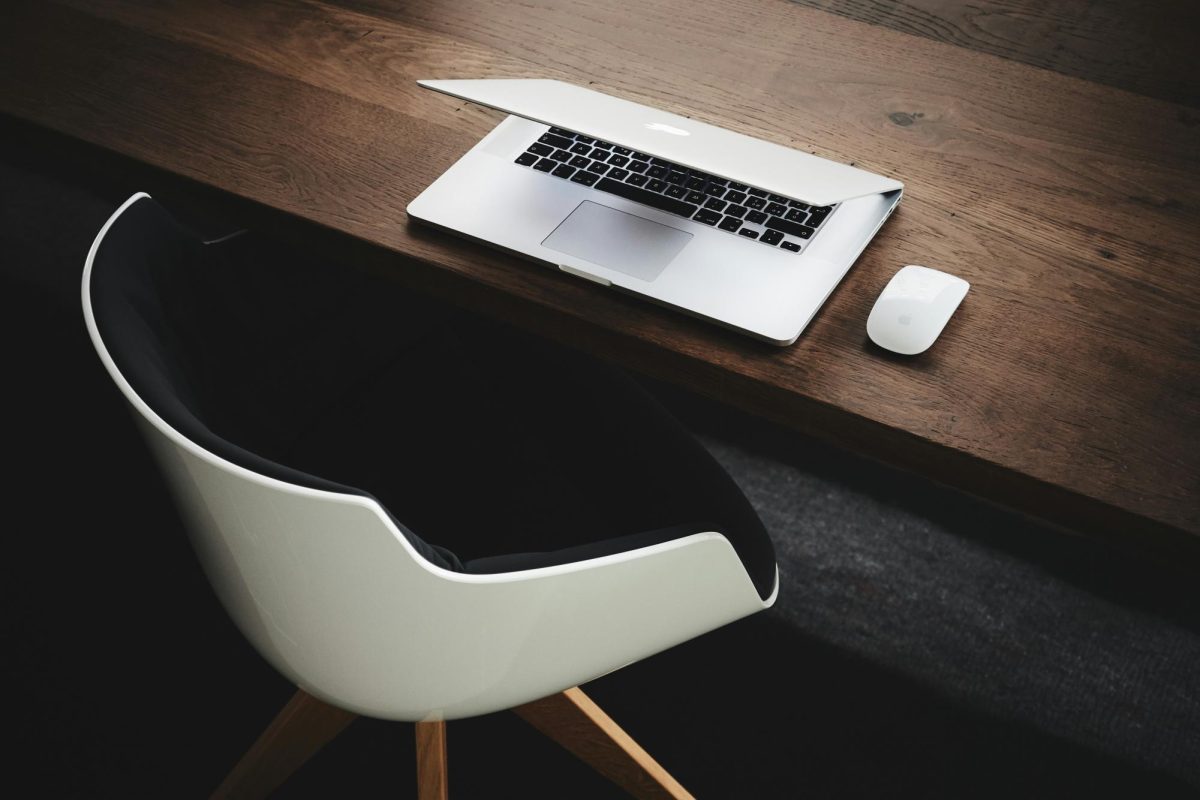 A macbook sits on a wooden desk half open