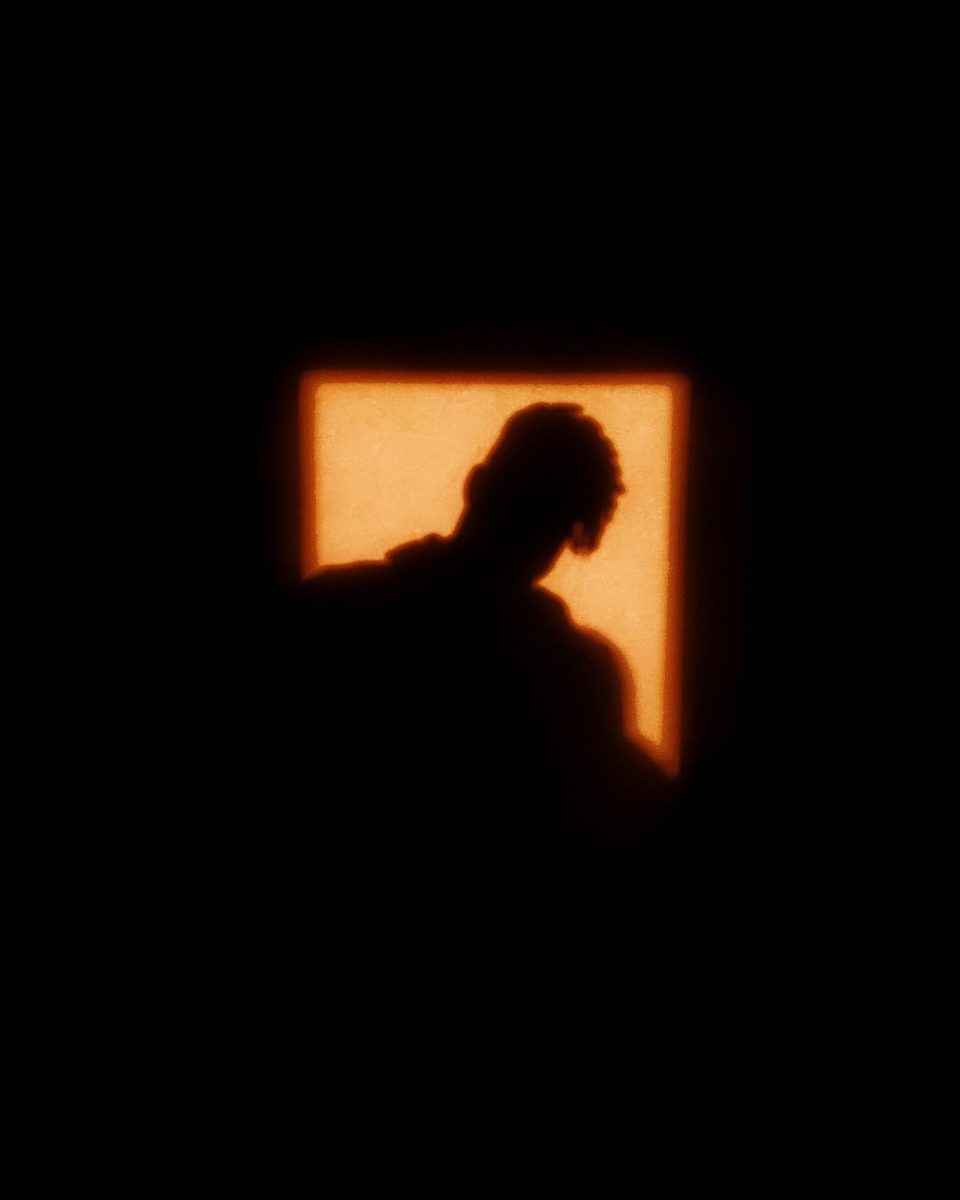 An ominous shadow of a man with square an orange light